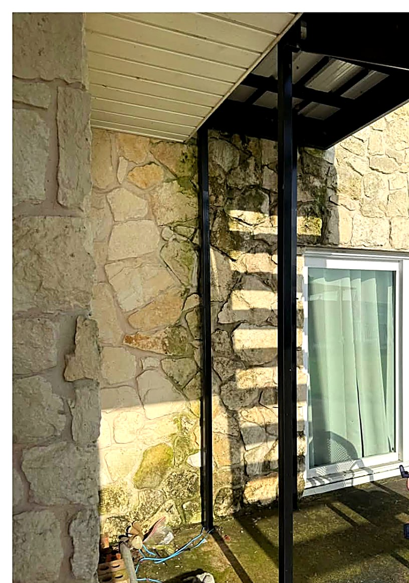 Mossy stone patio wall in shade before soft washing