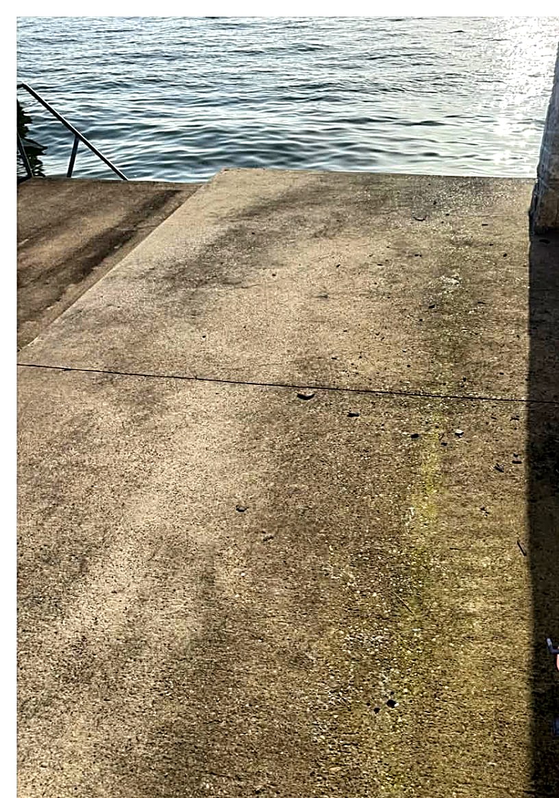 Lakeside concrete patio covered in algae before cleaning