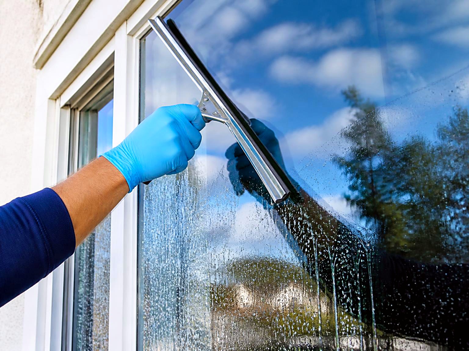 Professional squeegeeing a residential window to a streak-free finish